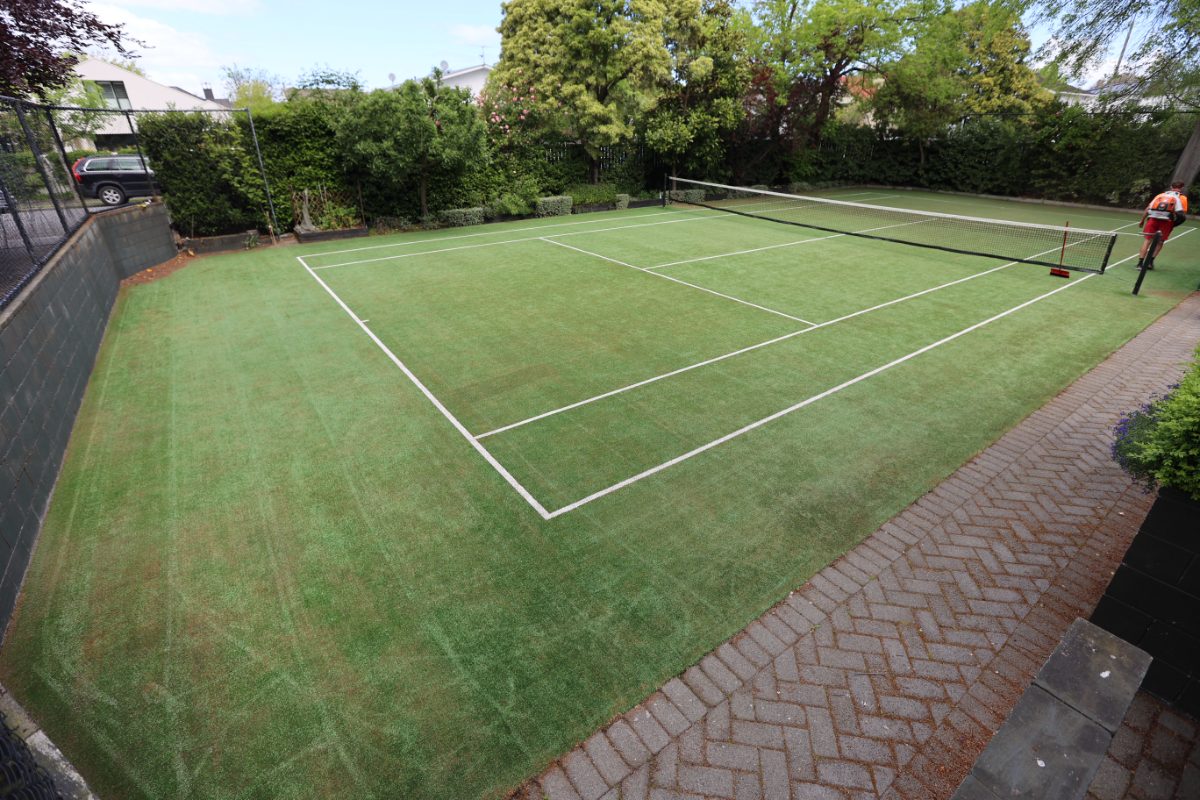 Backyard synthetic grass tennis court after grooming