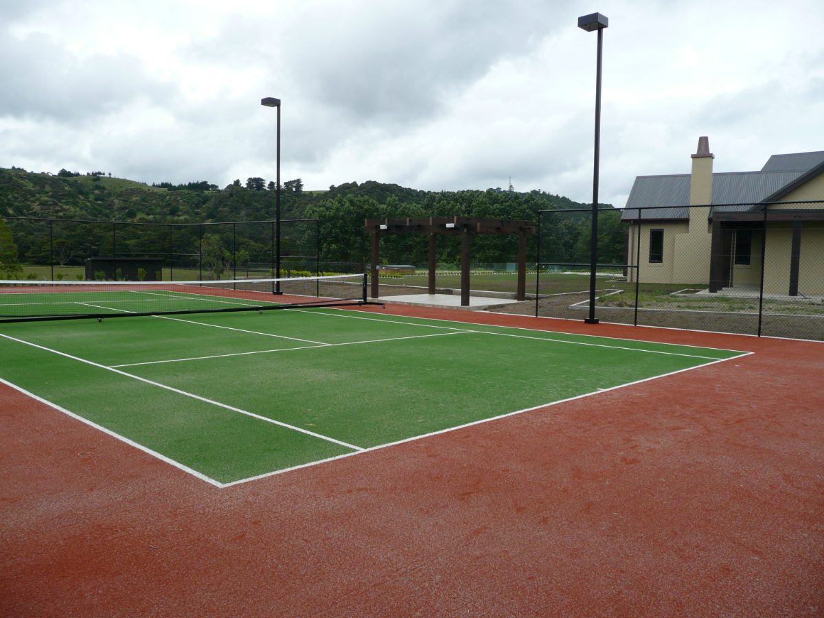 Restored green synthetic grass tennis court with red surrounds